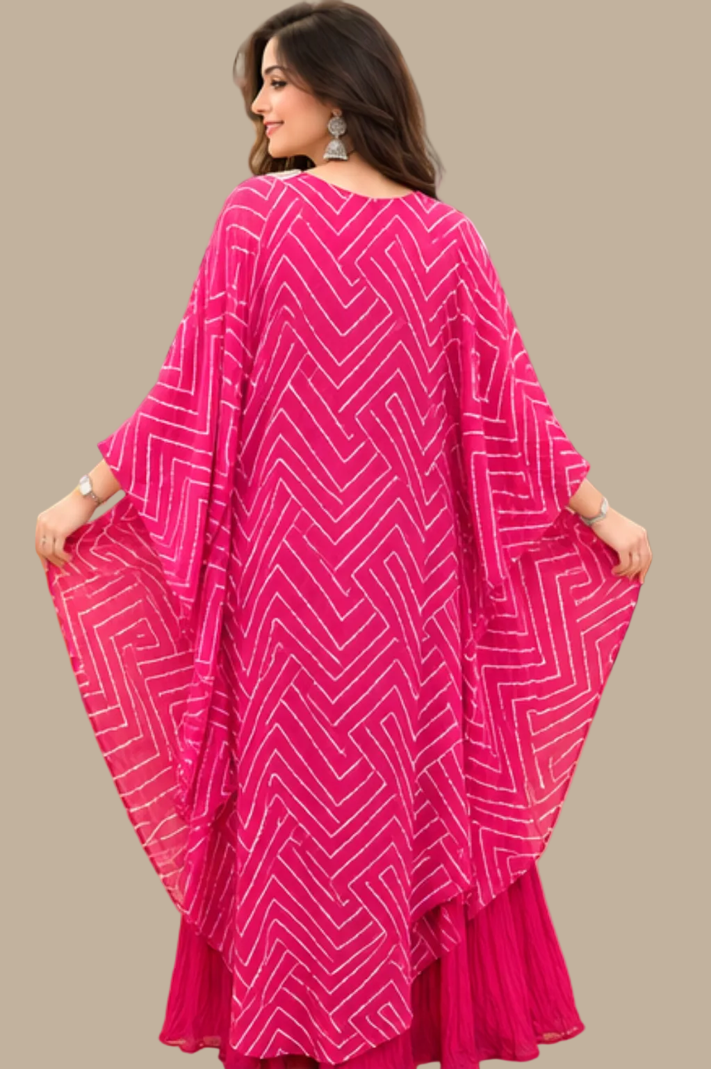 A woman seated in a yellow chair wearing a bright pink traditional outfit with a patterned embroidered bodice and a matching draped shawl, photographed in a retail store interior with shelves of folded garments in the background.